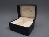 an open box with a watch inside of it on a gray surface