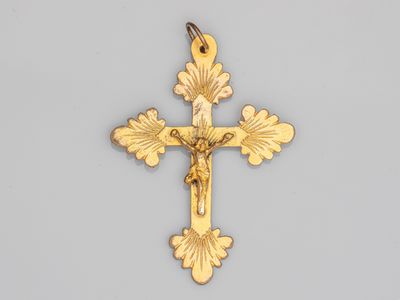 une croix en or sur laquelle figure Jésus, sur fond gris