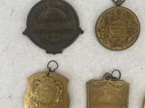 six medals of various sizes and shapes are displayed on a white surface