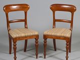 two wooden chairs with upholstered seats on a grey background
