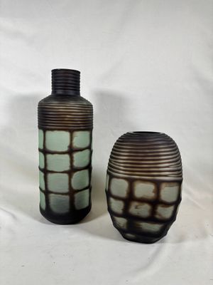 deux vases posés l'un à côté de l'autre sur une surface blanche