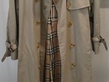 trench coat on a hanger in front of a white wall