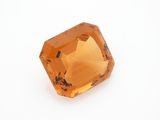an orange sapphire stone on a white surface