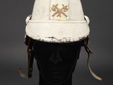 an old white fireman ' s helmet with a leather strap around the brim