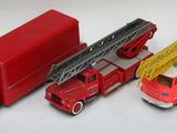 trois camions de pompiers miniatures et un camion posés sur une surface blanche