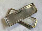 two silver trays sitting on a white surface