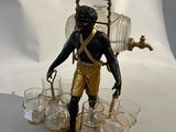 une figurine représentant un homme tenant une échelle et des verres