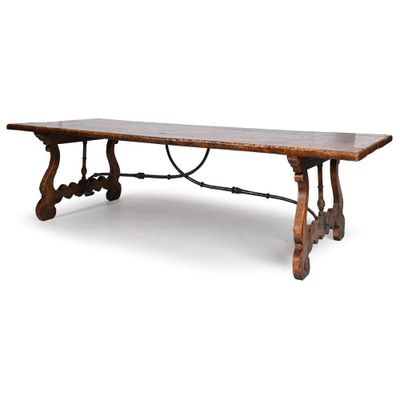 une vieille table en bois avec des pieds en fer forgé et un plateau en bois