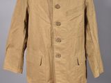 une veste beige à boutons rouges posée sur un présentoir pour mannequin