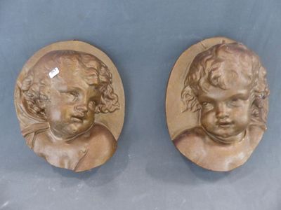 paire de plaques murales anciennes représentant des têtes d'enfants sur fond bleu