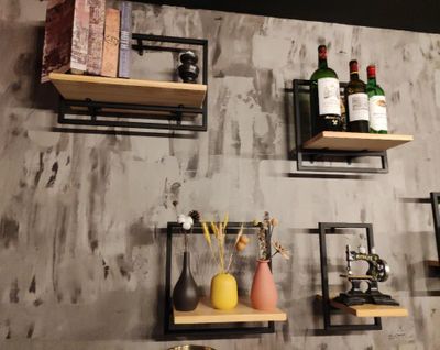 plusieurs étagères fixées au mur, sur lesquelles sont disposées des bouteilles et des vases