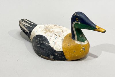 un canard en bois posé sur une surface blanche