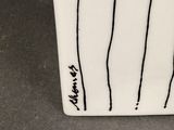 a white vase with black lines on it on a table