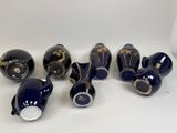 several blue vases with gold designs are lined up on a white surface