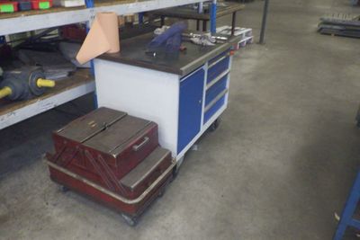 Plusieurs bagages sont empilés sur un chariot dans un entrepôt