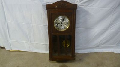 a clock that is sitting on the floor in front of a white wall