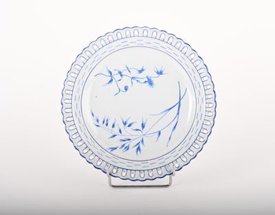 a blue and white plate on a stand on a white surface