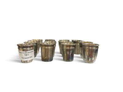 six silver shot glasses sitting next to each other on a white surface