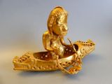 a gold figurine of a woman in a boat on a table