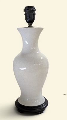 un vase blanc avec un socle noir posé sur une table