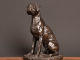 a bronze statue of a dog sitting on top of a wooden table
