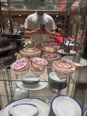 a man standing in front of a glass display case with plates and bowls