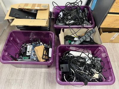trois bacs violets remplis d'appareils électroniques posés sur un parquet