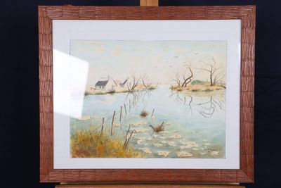 painting on easel of a lake with a house in the background