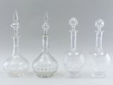 three glass decanters and a glass stopper on a white surface