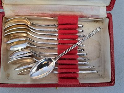 six cuillères dans un étui rouge posé sur une table