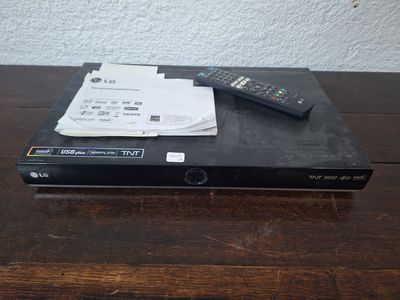 une télécommande posée sur un lecteur DVD, lui-même posé sur une table