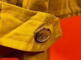 a close up of a yellow jacket with a button on it