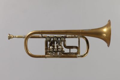 a brass trumpet that is sitting on a white surface