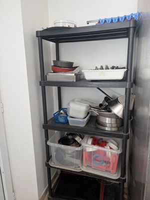 une étagère sur laquelle sont posés des casseroles et des poêles, dans un coin de la pièce