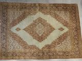 un vieux tapis à motifs losangés posé sur un sol blanc