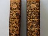 two old books are sitting side by side on a white surface