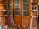 a wooden bookcase with glass doors in the corner of a room