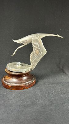 an image of a statue of a bird flying over a wooden base