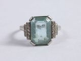 a close up of a ring on a white surface with a green stone