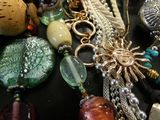many different necklaces and bracelets laid out on a table