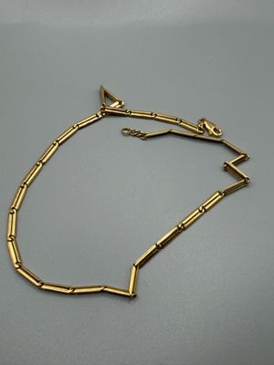 gros plan d'un bracelet en or sur une surface grise