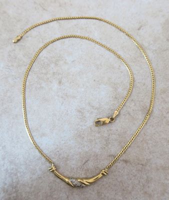 gros plan d'un collier en or sur une surface blanche