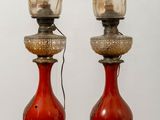 pair of red glass lamps on a wooden table against a white wall