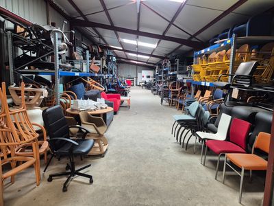 des rangées de chaises et de tables dans un entrepôt rempli de meubles
