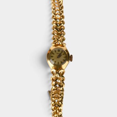 Gros plan sur une montre-bracelet en or entourée d'une chaîne