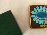 a small blue flower on a brown and green tile
