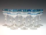 six verres à vin transparents sont alignés en rang sur une surface blanche