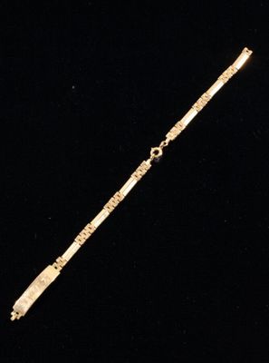 a gold bracelet with a cross on it on a black background