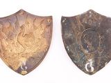 two metal shields with numbers on them on a white surface