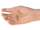 a hand holding a small gold cross on it ' s palm